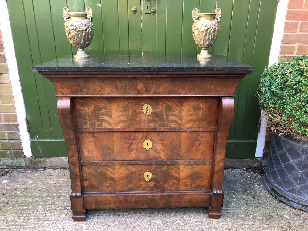 An early nineteenth-century French Empire mahogany commode featuring three drawers with flame mahogany veneer, brass escutcheons, and a thick dark fossil marble top. View XXII