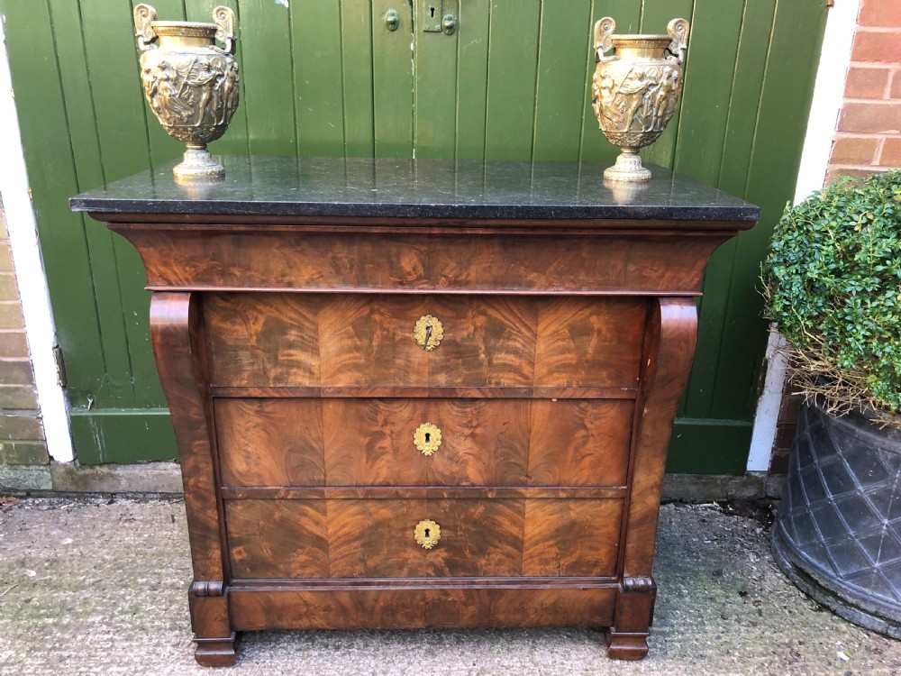 An early nineteenth-century French Empire mahogany commode featuring three drawers with flame mahogany veneer, brass escutcheons, and a thick dark fossil marble top. View XXIV
