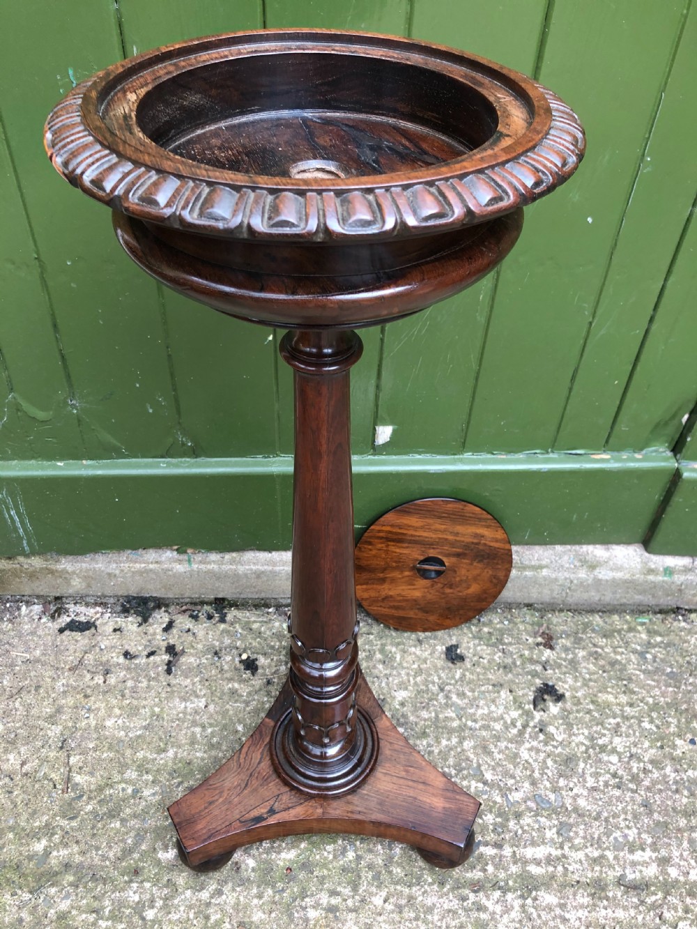 An early 19th-century carved rosewood jardiniere stand featuring a gadrooned top rim, turned column shaft, and a triform base. View X