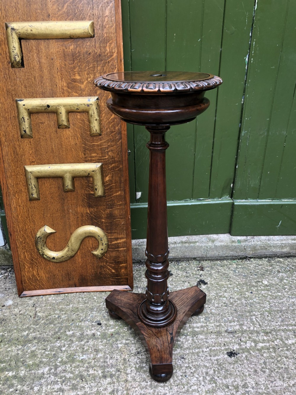 An early 19th-century carved rosewood jardiniere stand featuring a gadrooned top rim, turned column shaft, and a triform base. View XVI