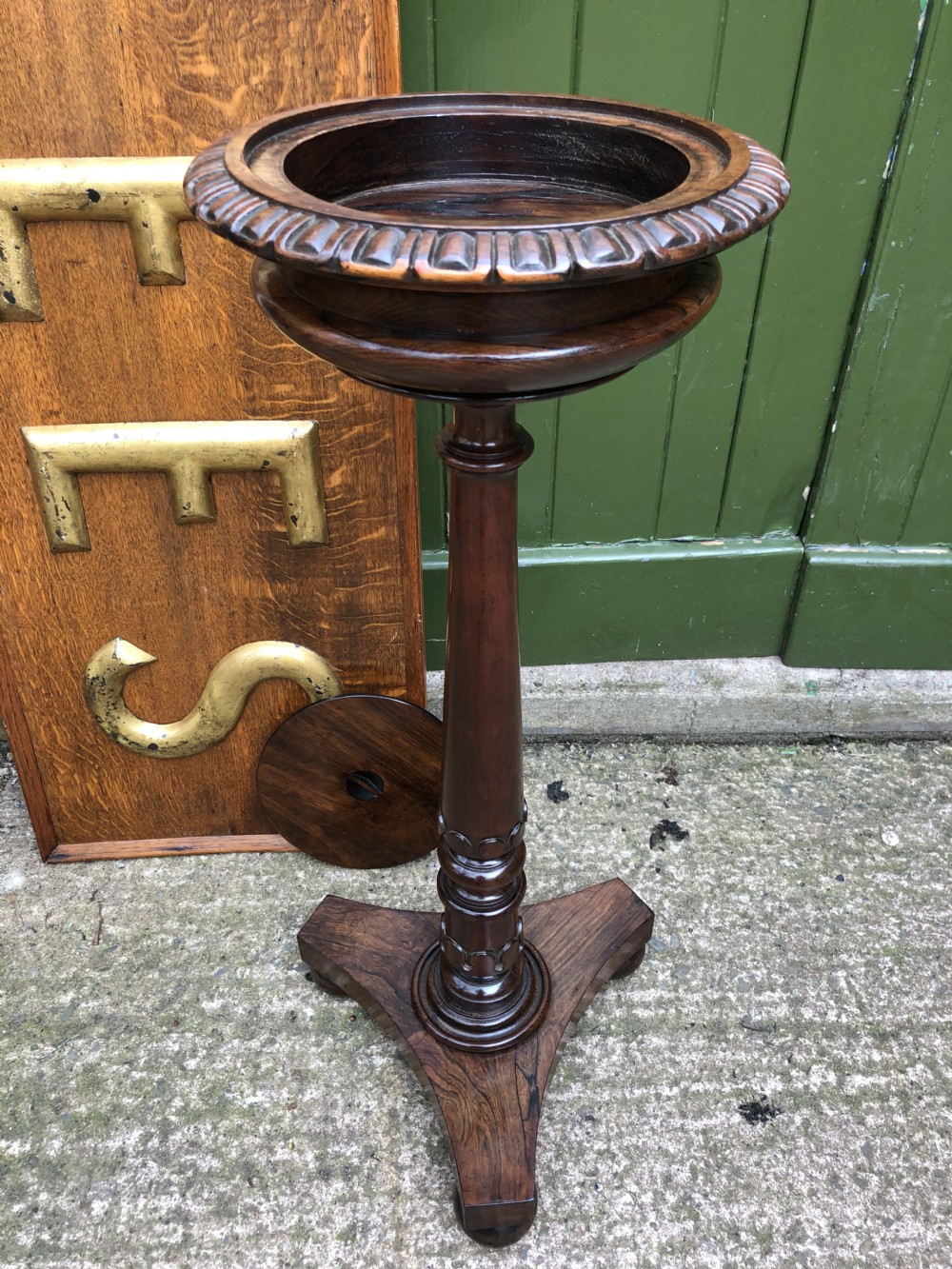 An early 19th-century carved rosewood jardiniere stand featuring a gadrooned top rim, turned column shaft, and a triform base. View XVIII