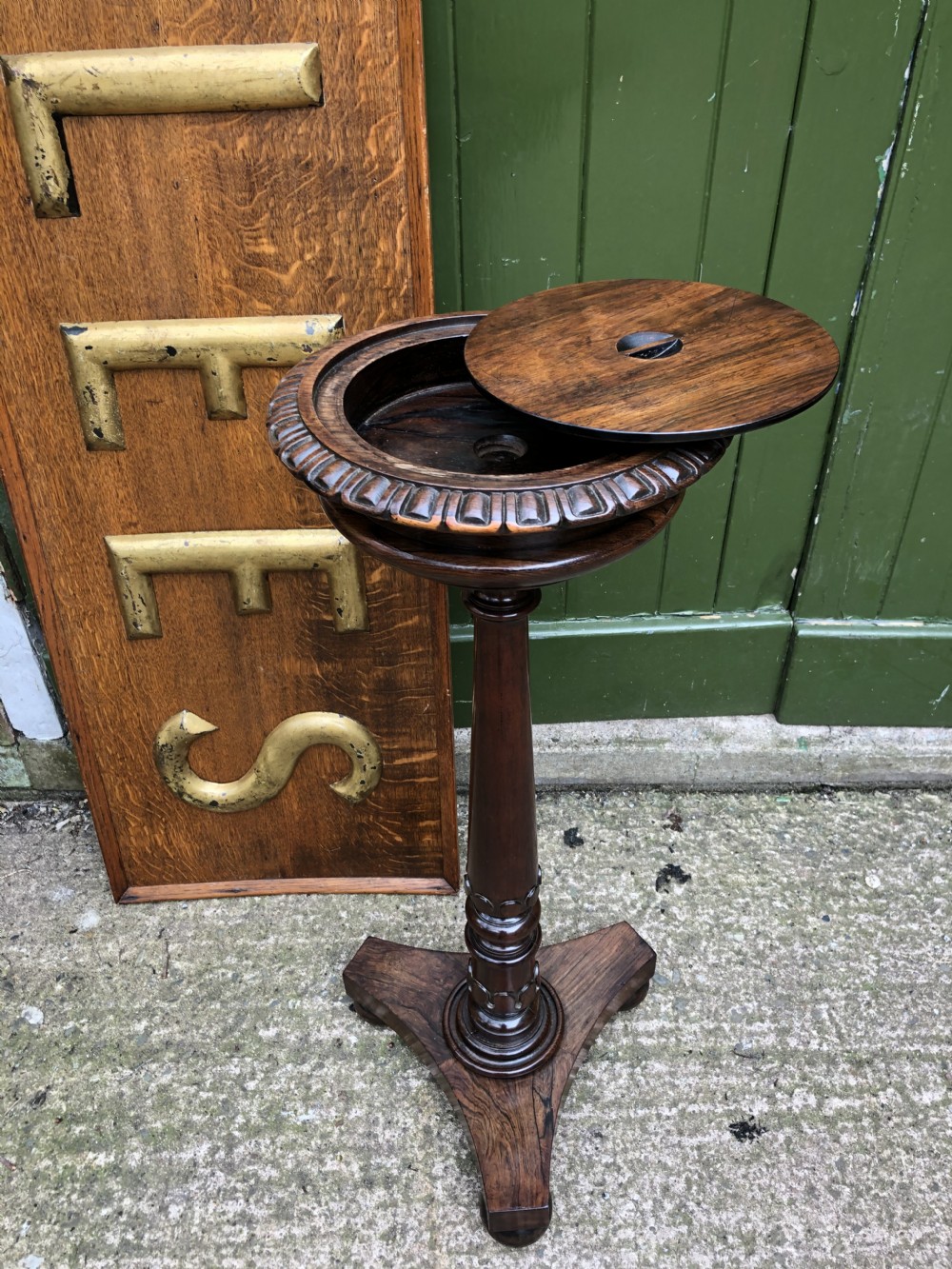 An early 19th-century carved rosewood jardiniere stand featuring a gadrooned top rim, turned column shaft, and a triform base. View XIX