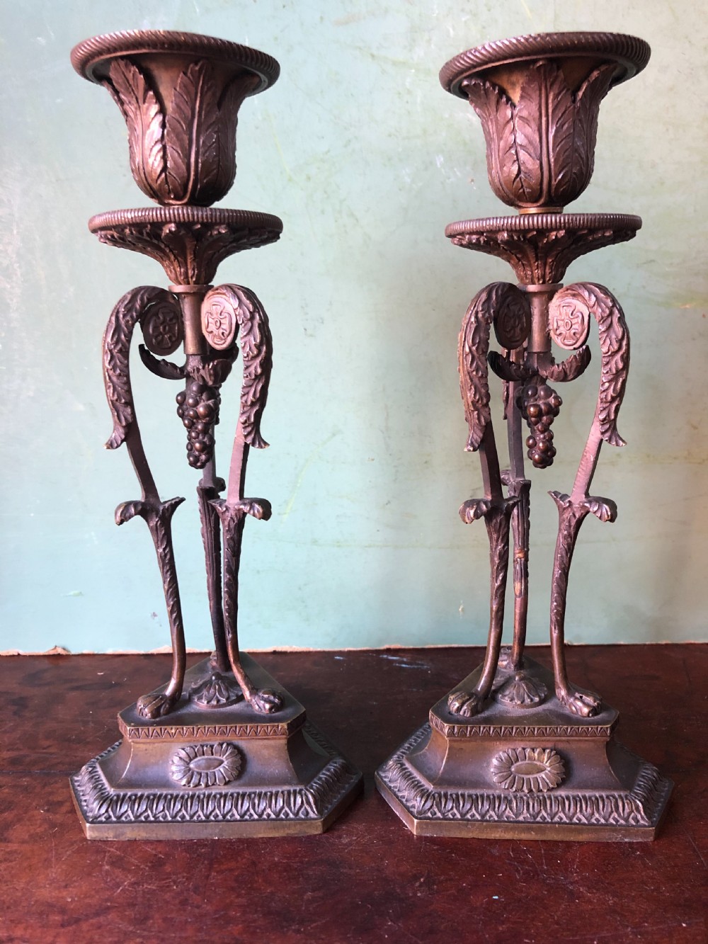 A pair of early nineteenth-century Regency bronze candlesticks designed in classical Athenienne tripod form with leaf sconces and plinth bases. View II