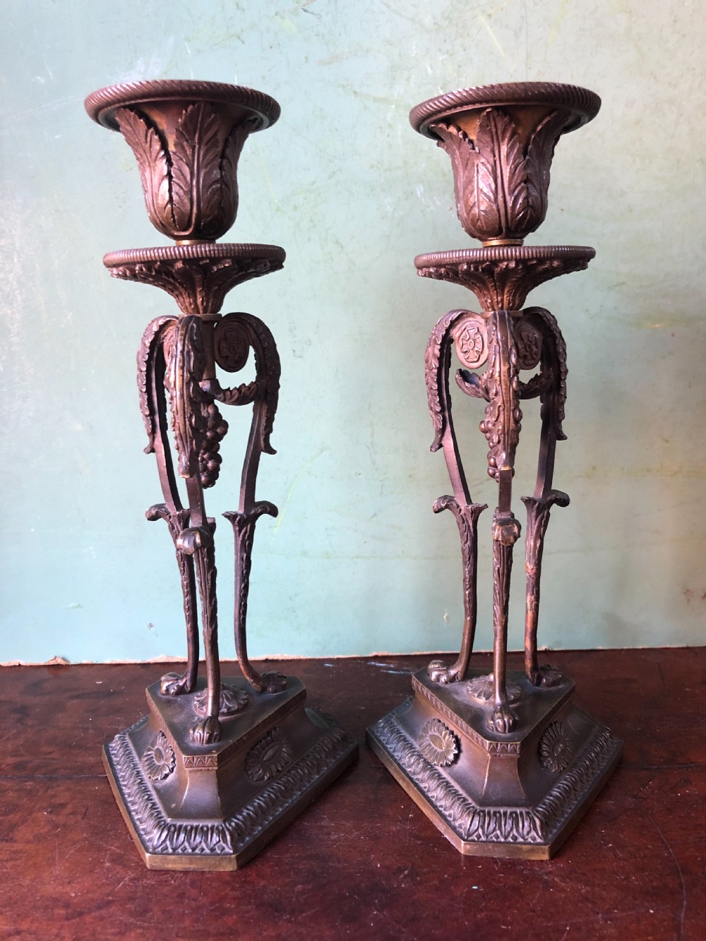 A pair of early nineteenth-century Regency bronze candlesticks designed in classical Athenienne tripod form with leaf sconces and plinth bases. View III