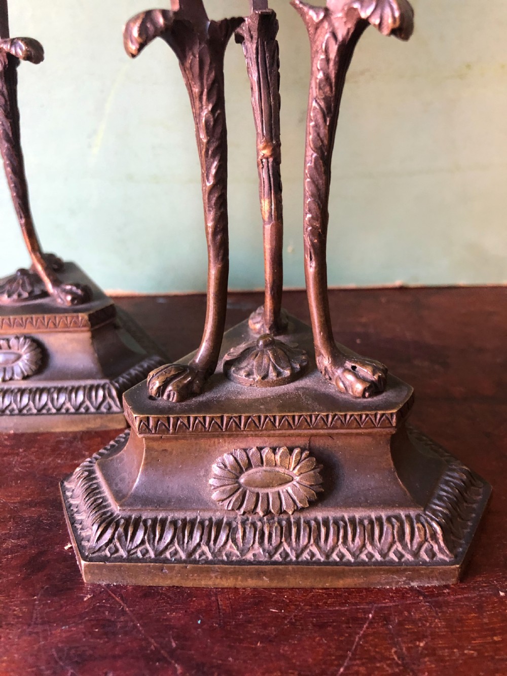 A pair of early nineteenth-century Regency bronze candlesticks designed in classical Athenienne tripod form with leaf sconces and plinth bases. View XVII
