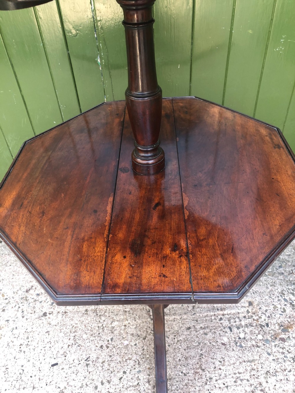 A late eighteenth-century George III mahogany two-tier dumb waiter table featuring octagonal drop-leaf surfaces supported by a turned central column on tripod legs with brass castors. View V