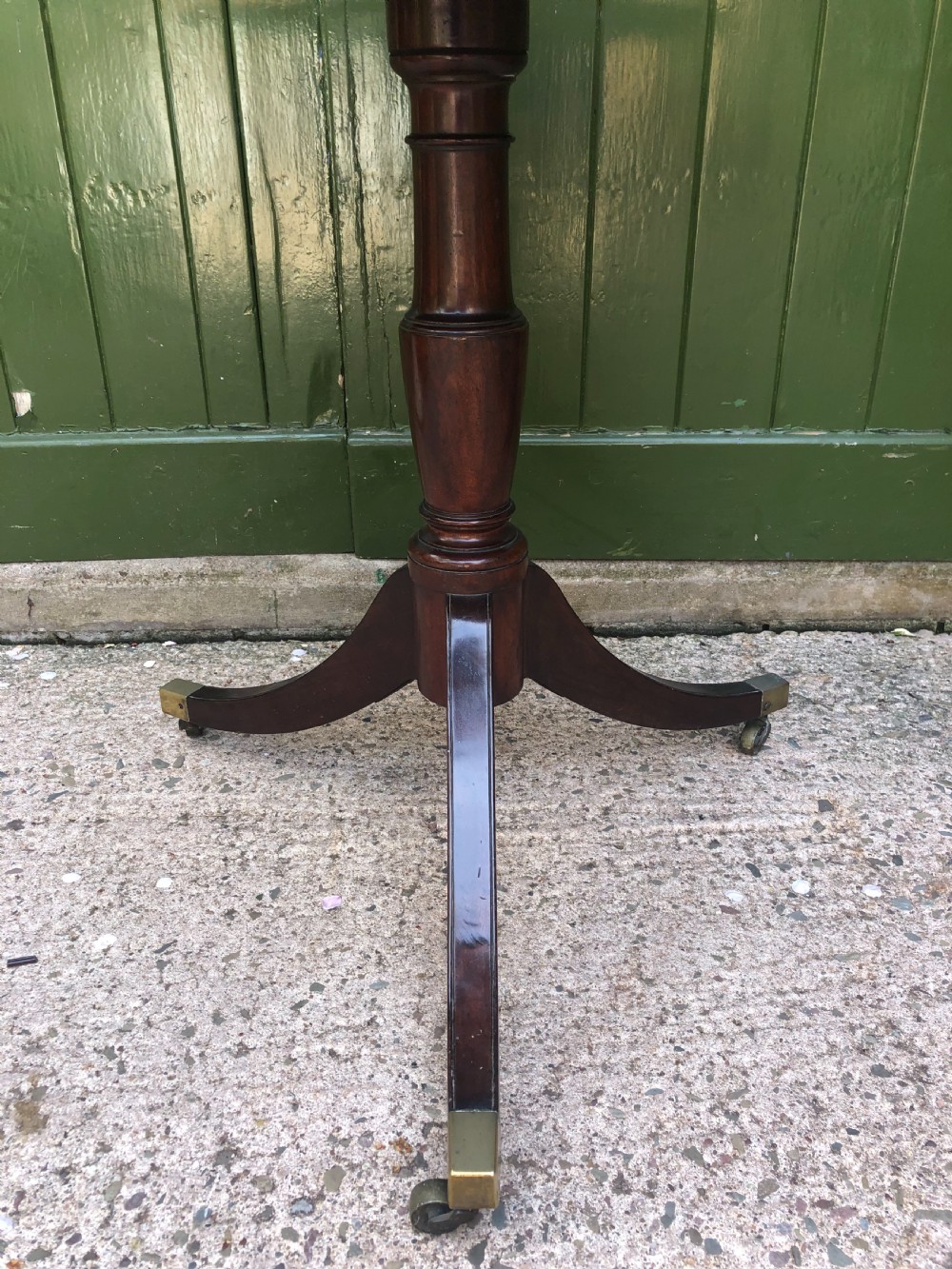 A late eighteenth-century George III mahogany two-tier dumb waiter table featuring octagonal drop-leaf surfaces supported by a turned central column on tripod legs with brass castors. View IX