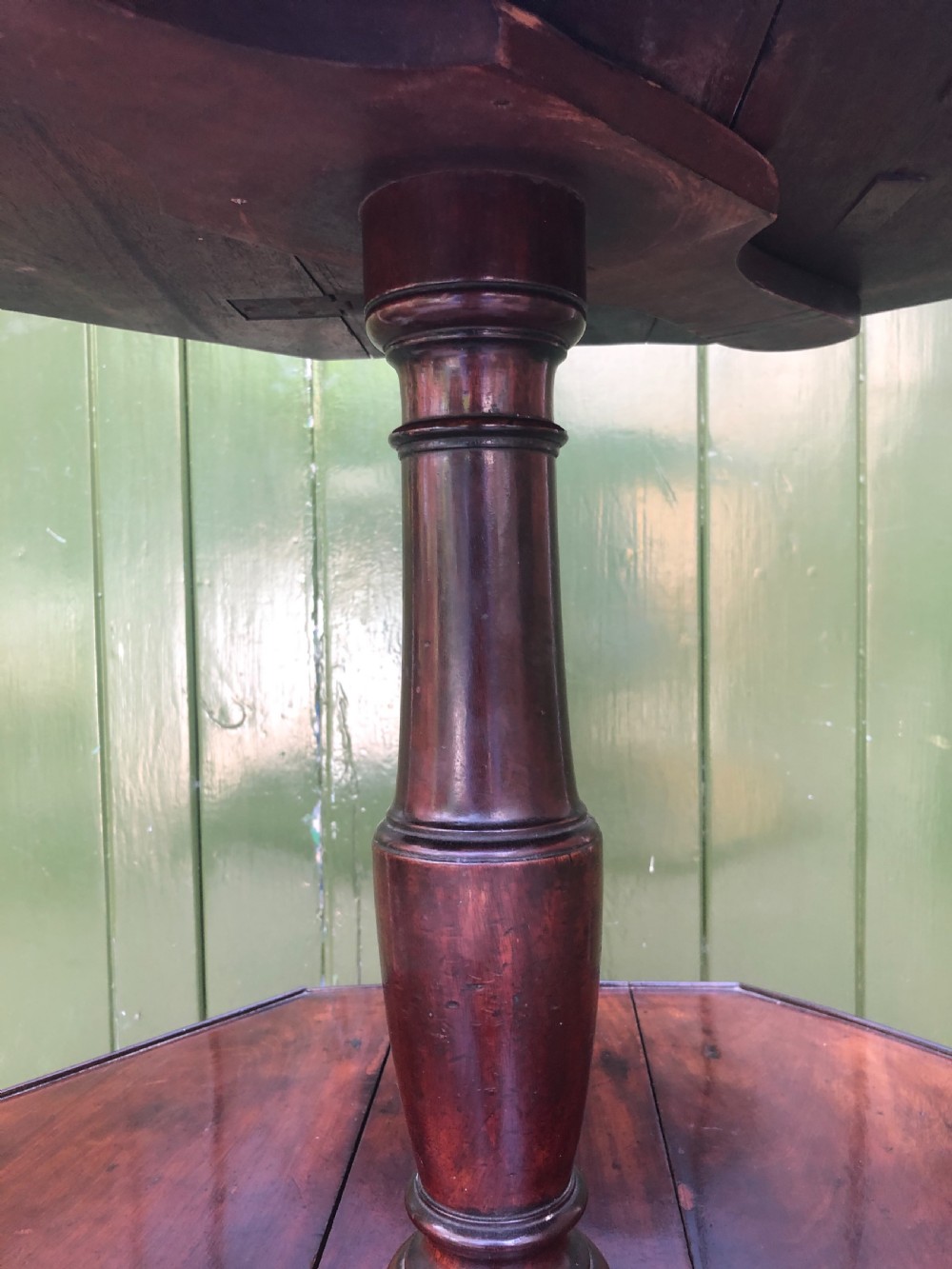 A late eighteenth-century George III mahogany two-tier dumb waiter table featuring octagonal drop-leaf surfaces supported by a turned central column on tripod legs with brass castors. View X