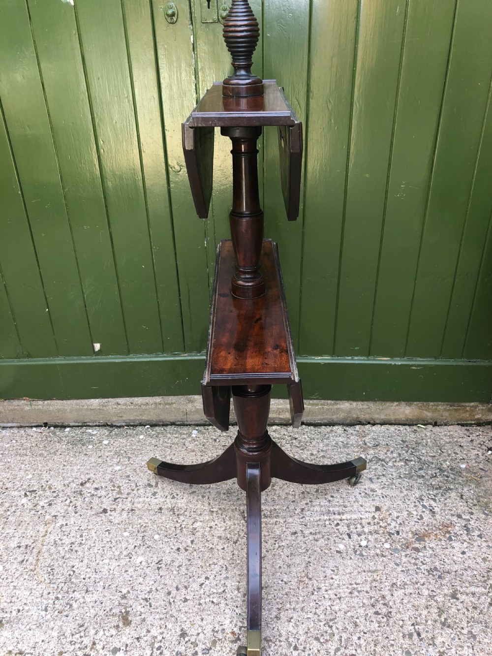 A late eighteenth-century George III mahogany two-tier dumb waiter table featuring octagonal drop-leaf surfaces supported by a turned central column on tripod legs with brass castors. View XI