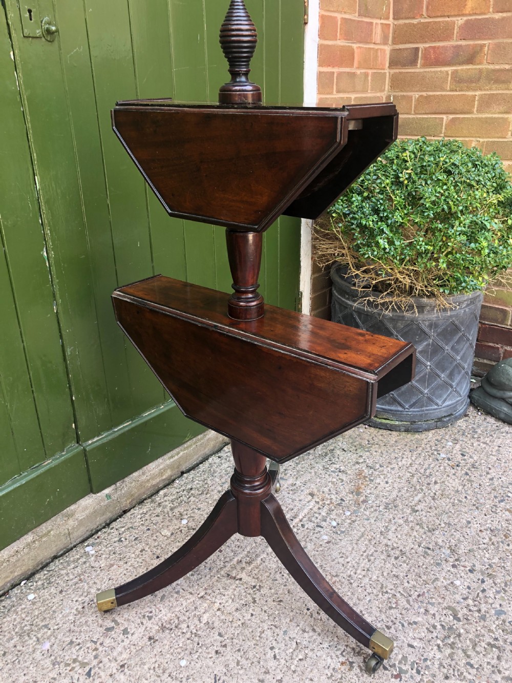 A late eighteenth-century George III mahogany two-tier dumb waiter table featuring octagonal drop-leaf surfaces supported by a turned central column on tripod legs with brass castors. View XIII