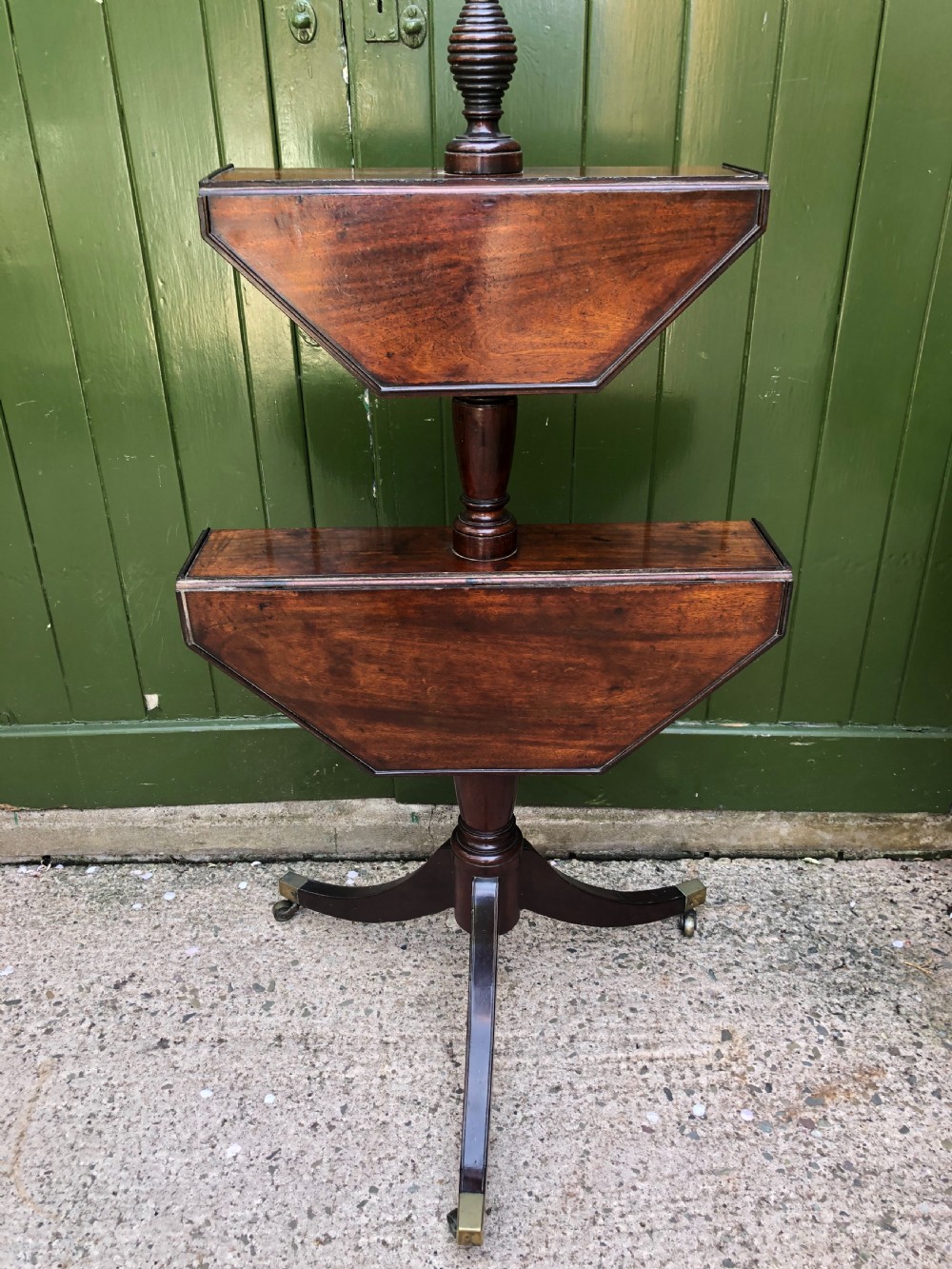 A late eighteenth-century George III mahogany two-tier dumb waiter table featuring octagonal drop-leaf surfaces supported by a turned central column on tripod legs with brass castors. View XIV