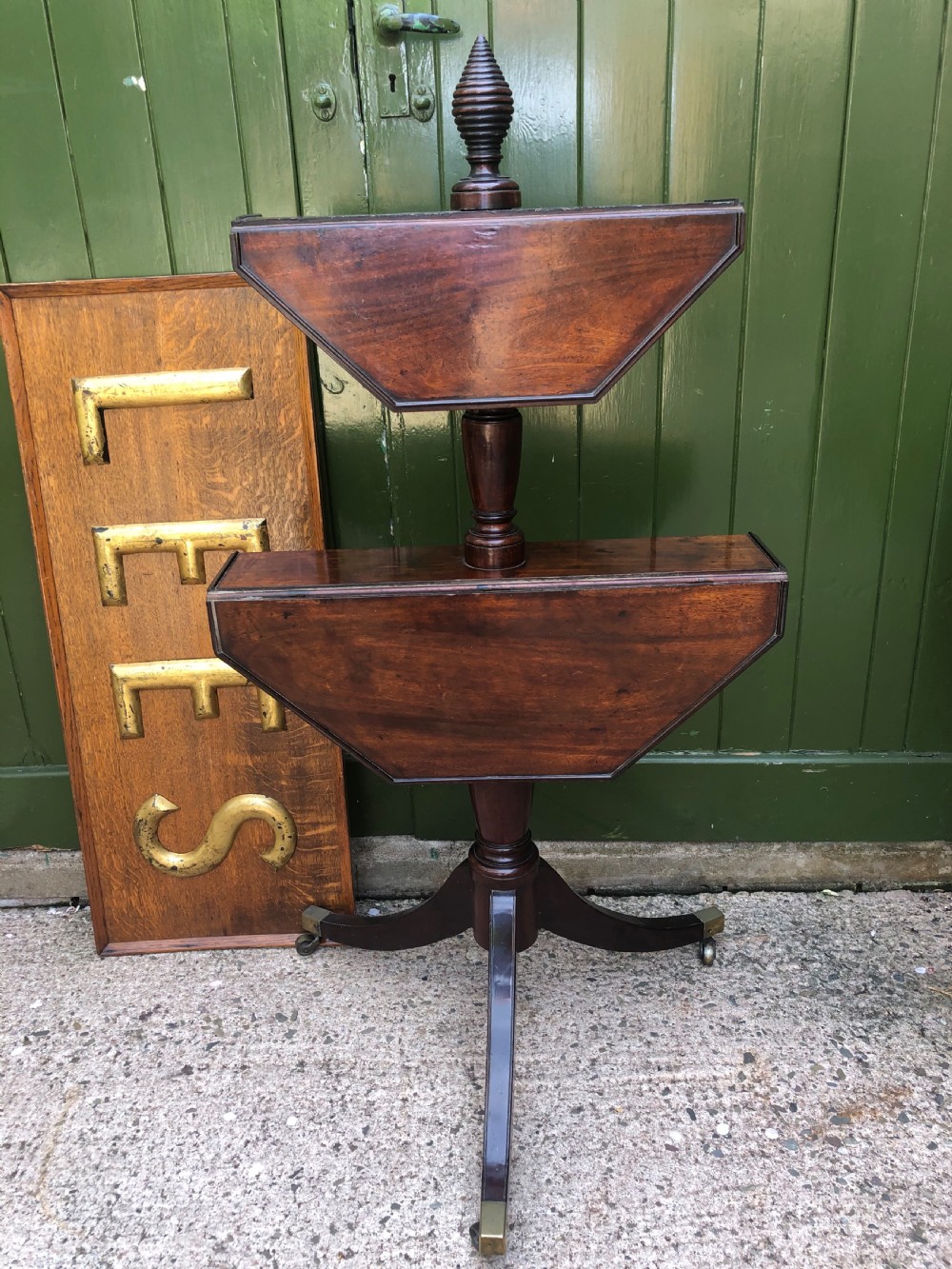 A late eighteenth-century George III mahogany two-tier dumb waiter table featuring octagonal drop-leaf surfaces supported by a turned central column on tripod legs with brass castors. View XVII