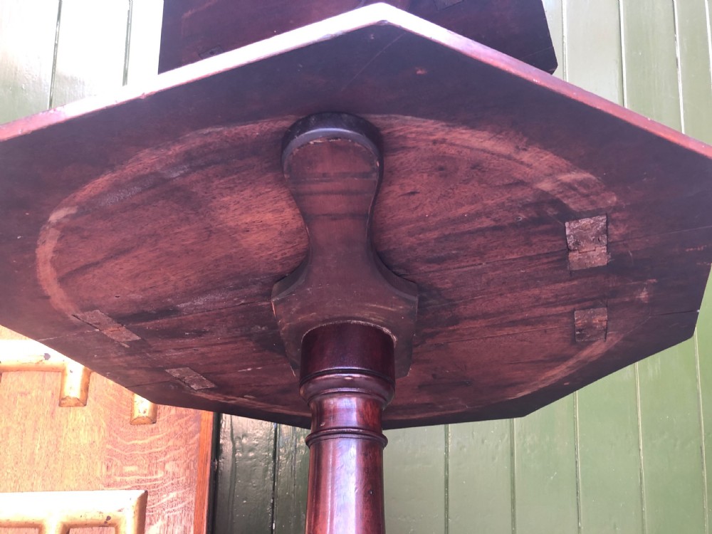 A late eighteenth-century George III mahogany two-tier dumb waiter table featuring octagonal drop-leaf surfaces supported by a turned central column on tripod legs with brass castors. View XX