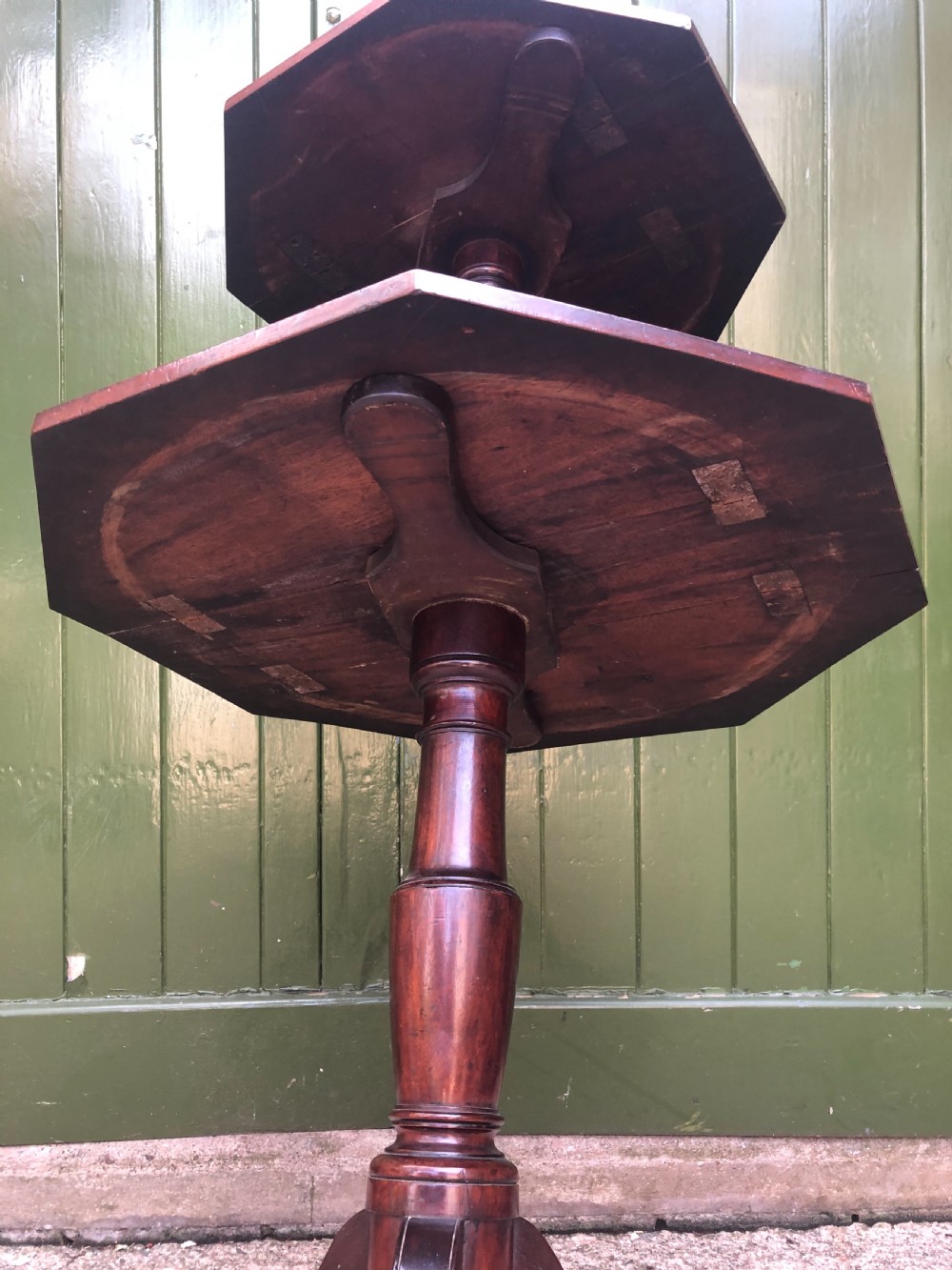 A late eighteenth-century George III mahogany two-tier dumb waiter table featuring octagonal drop-leaf surfaces supported by a turned central column on tripod legs with brass castors. View XXI