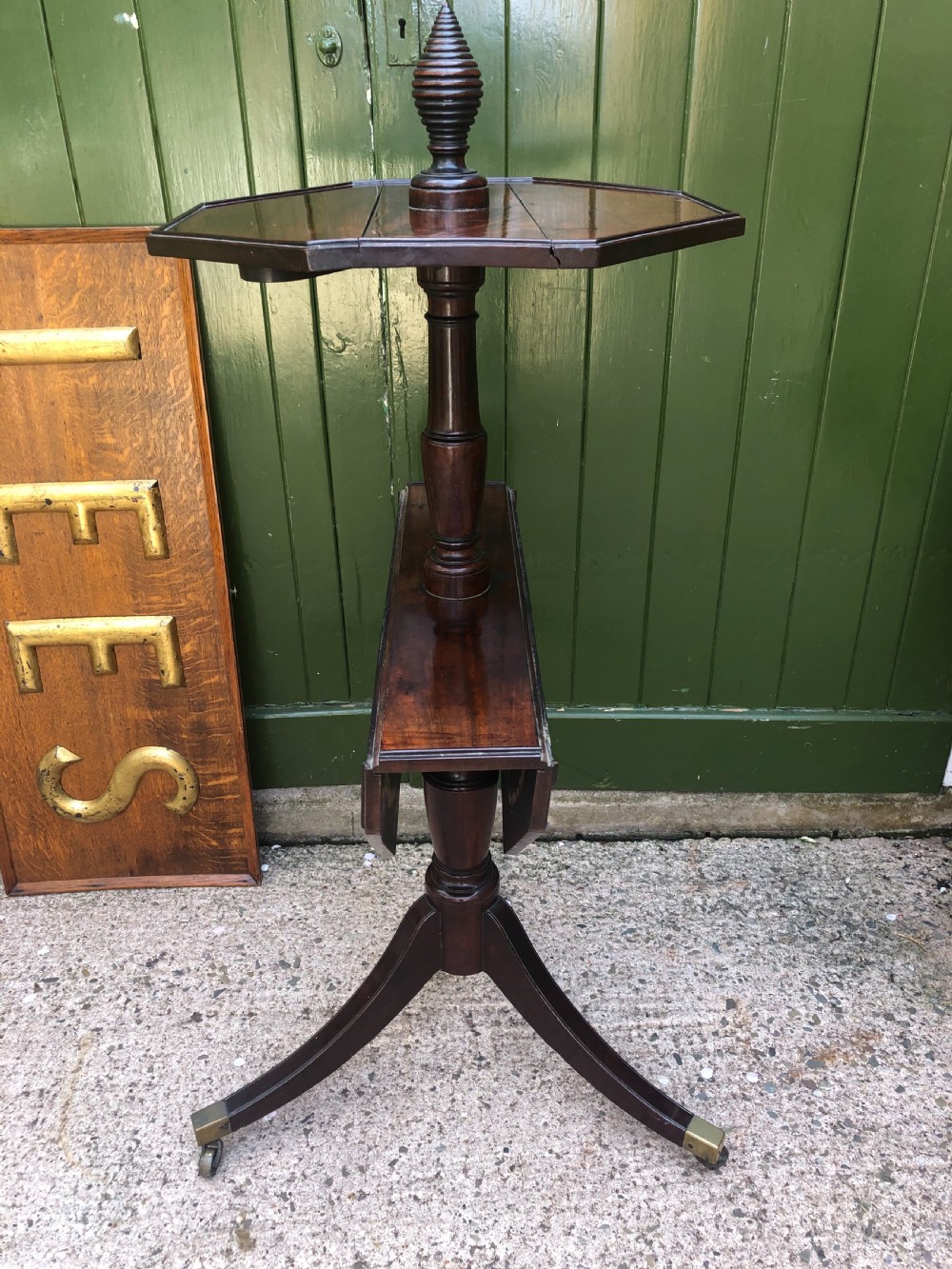 A late eighteenth-century George III mahogany two-tier dumb waiter table featuring octagonal drop-leaf surfaces supported by a turned central column on tripod legs with brass castors. View XXIII