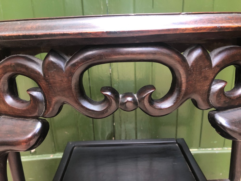 A 19th-century Chinese dark hardwood demi-lune console table featuring an inset variegated marble top, openwork carved frieze, and lower tier shelving. View V