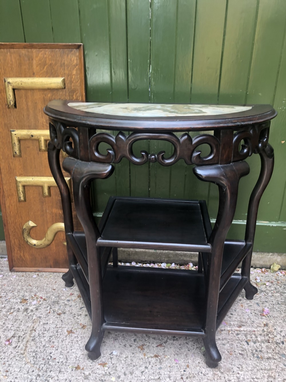 A 19th-century Chinese dark hardwood demi-lune console table featuring an inset variegated marble top, openwork carved frieze, and lower tier shelving. View VI