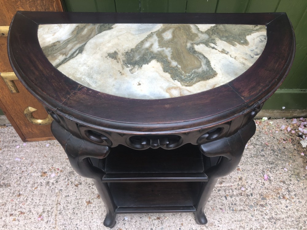A 19th-century Chinese dark hardwood demi-lune console table featuring an inset variegated marble top, openwork carved frieze, and lower tier shelving. View VIII