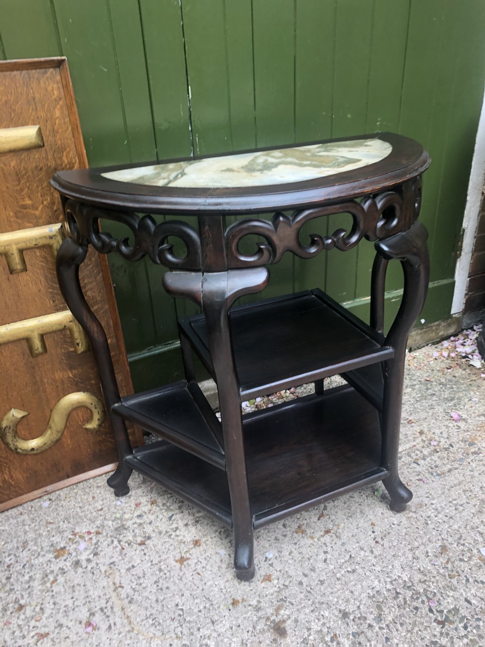 A 19th-century Chinese dark hardwood demi-lune console table featuring an inset variegated marble top, openwork carved frieze, and lower tier shelving. View IX