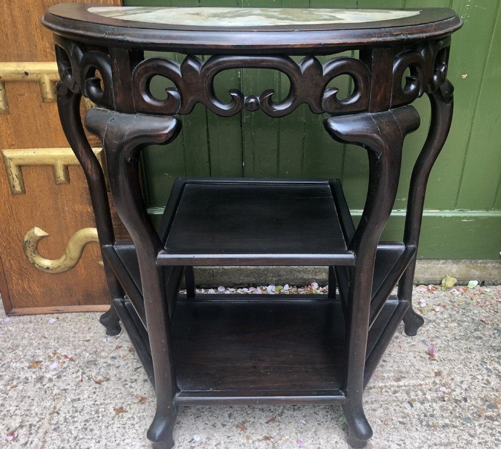 A 19th-century Chinese dark hardwood demi-lune console table featuring an inset variegated marble top, openwork carved frieze, and lower tier shelving. View XI