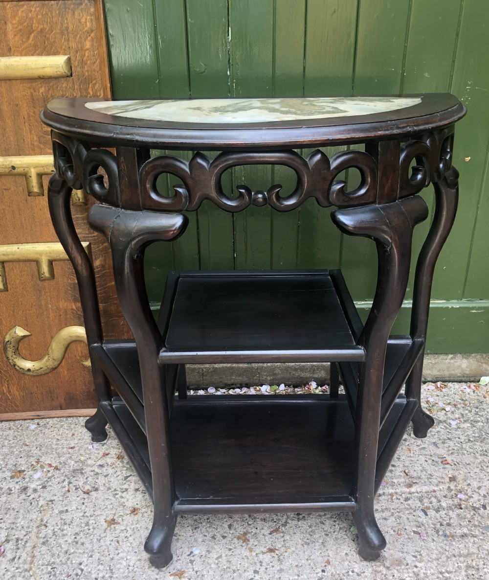 A 19th-century Chinese dark hardwood demi-lune console table featuring an inset variegated marble top, openwork carved frieze, and lower tier shelving. View II