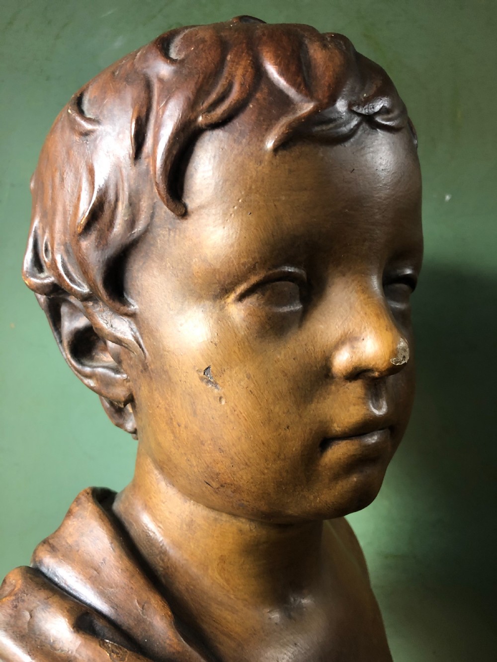 An early nineteenth-century patinated plaster bust of a young boy with draped shoulder fabric, set on a turned circular pedestal base. View VI