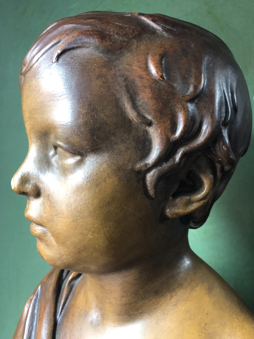 An early nineteenth-century patinated plaster bust of a young boy with draped shoulder fabric, set on a turned circular pedestal base. View VII