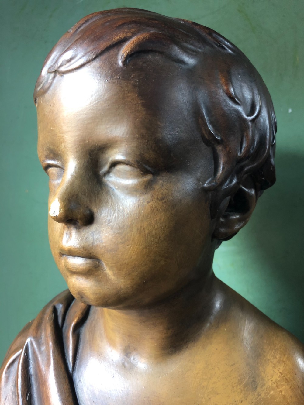 An early nineteenth-century patinated plaster bust of a young boy with draped shoulder fabric, set on a turned circular pedestal base. View VIII