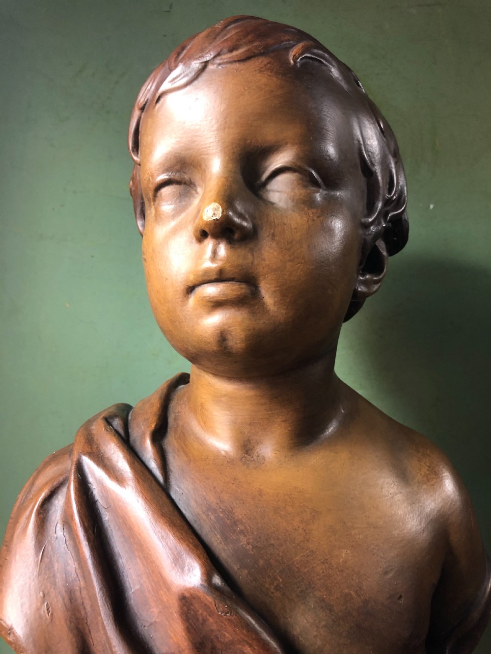 An early nineteenth-century patinated plaster bust of a young boy with draped shoulder fabric, set on a turned circular pedestal base. View IX
