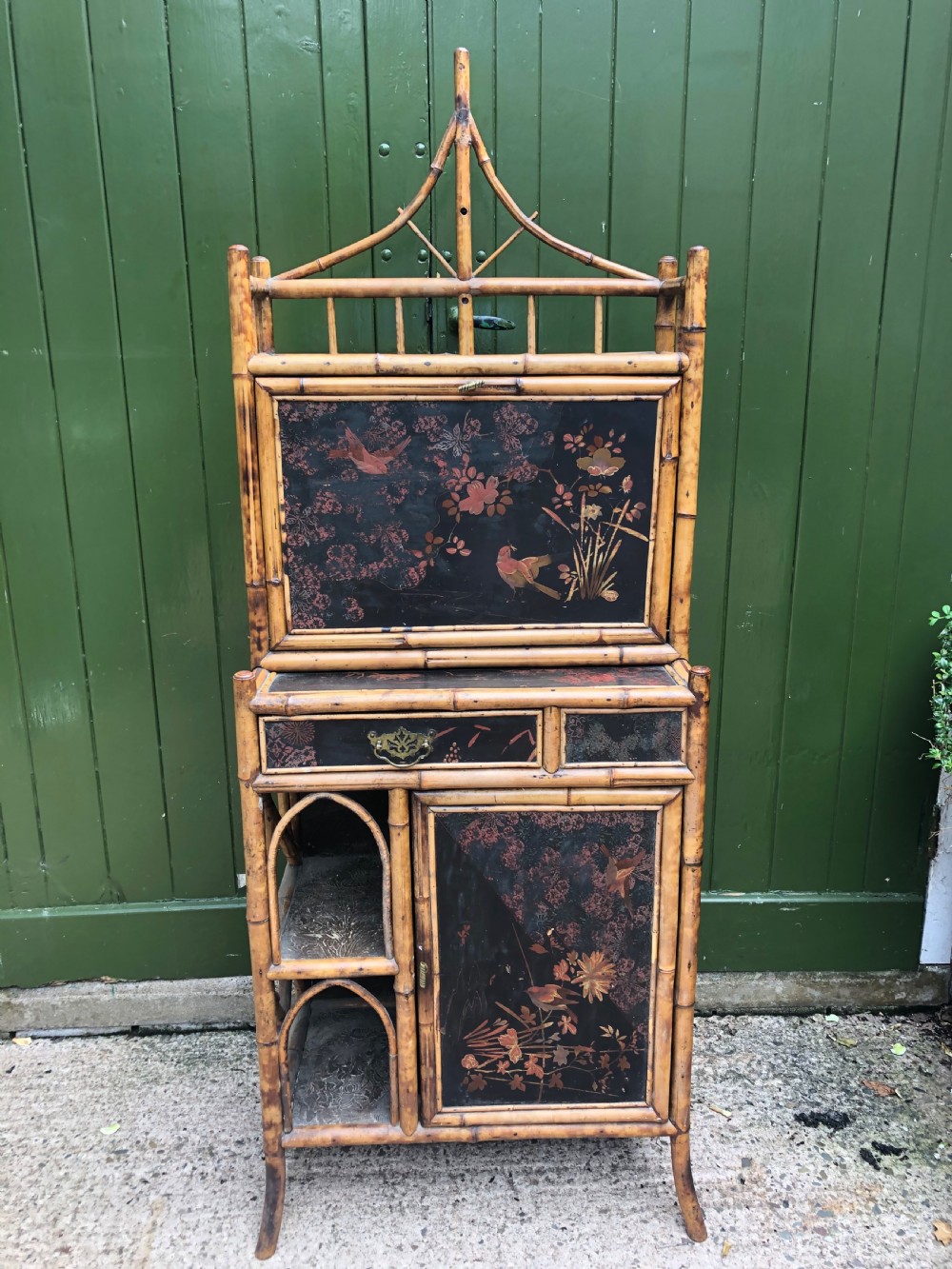 A late 19th-century bamboo escritoire cabinet featuring a pagoda-shaped top finial, a lacquered drop-front writing slope, side shelves, and a lower lacquered cupboard door decorated with floral motifs. View II