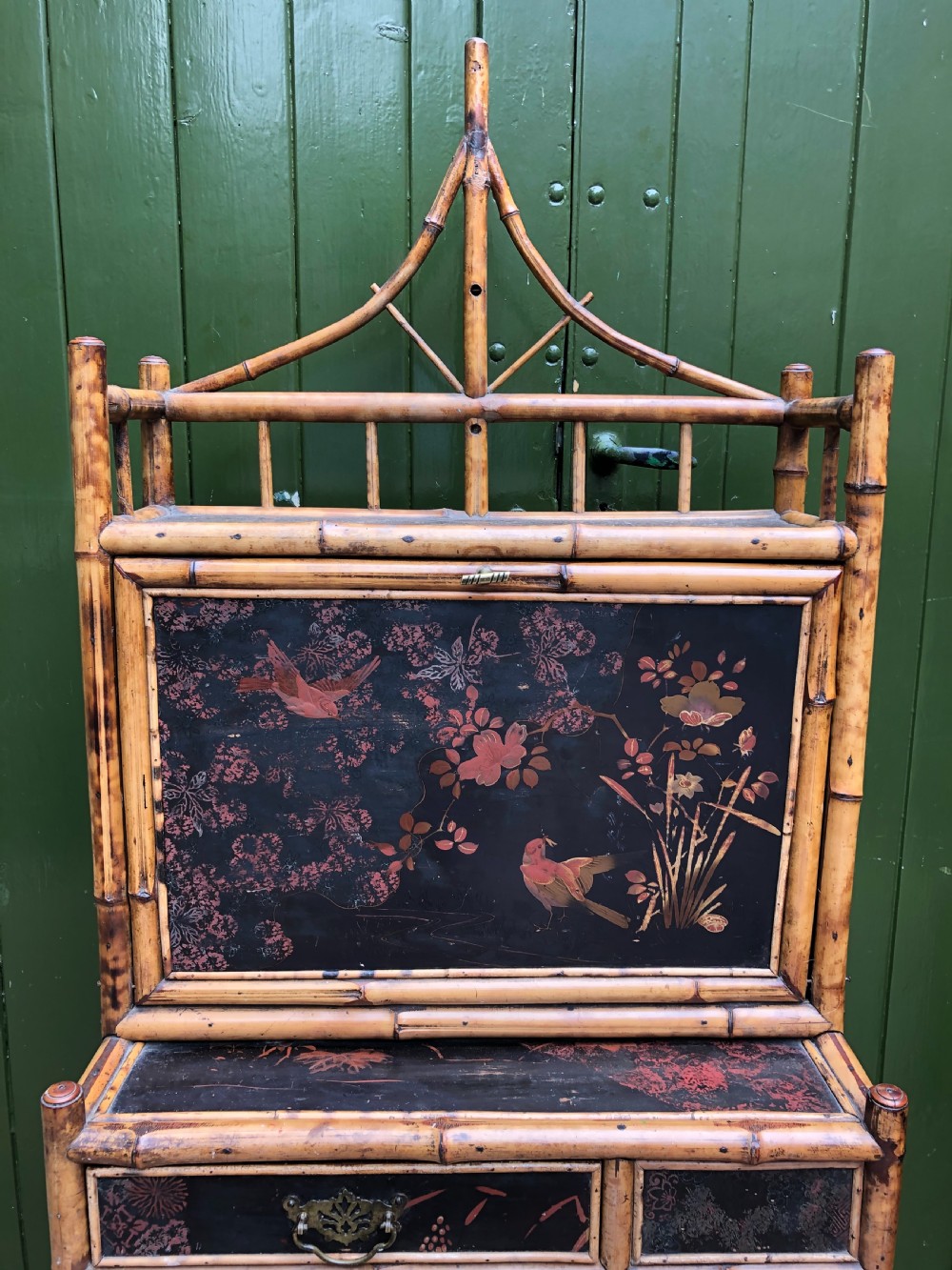 A late 19th-century bamboo escritoire cabinet featuring a pagoda-shaped top finial, a lacquered drop-front writing slope, side shelves, and a lower lacquered cupboard door decorated with floral motifs. View XI