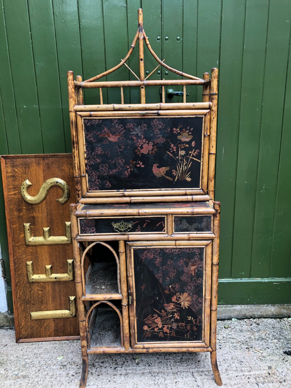 A late 19th-century bamboo escritoire cabinet featuring a pagoda-shaped top finial, a lacquered drop-front writing slope, side shelves, and a lower lacquered cupboard door decorated with floral motifs. View XII