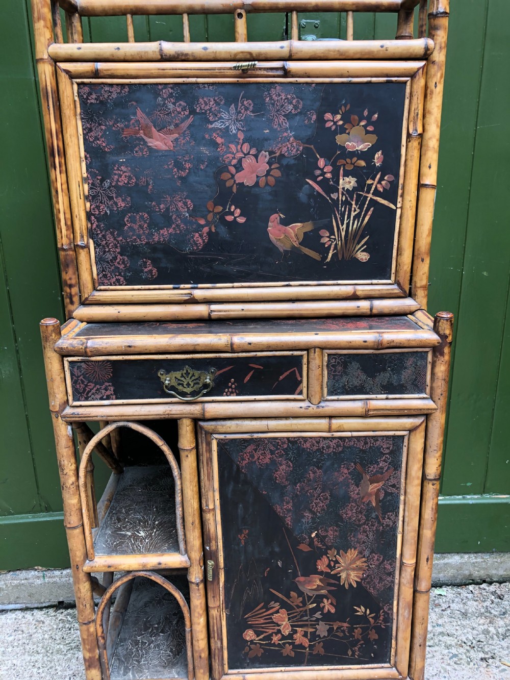 A late 19th-century bamboo escritoire cabinet featuring a pagoda-shaped top finial, a lacquered drop-front writing slope, side shelves, and a lower lacquered cupboard door decorated with floral motifs. View XVII