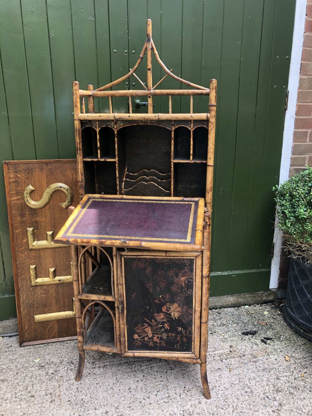 A late 19th-century bamboo escritoire cabinet featuring a pagoda-shaped top finial, a lacquered drop-front writing slope, side shelves, and a lower lacquered cupboard door decorated with floral motifs. View XXII