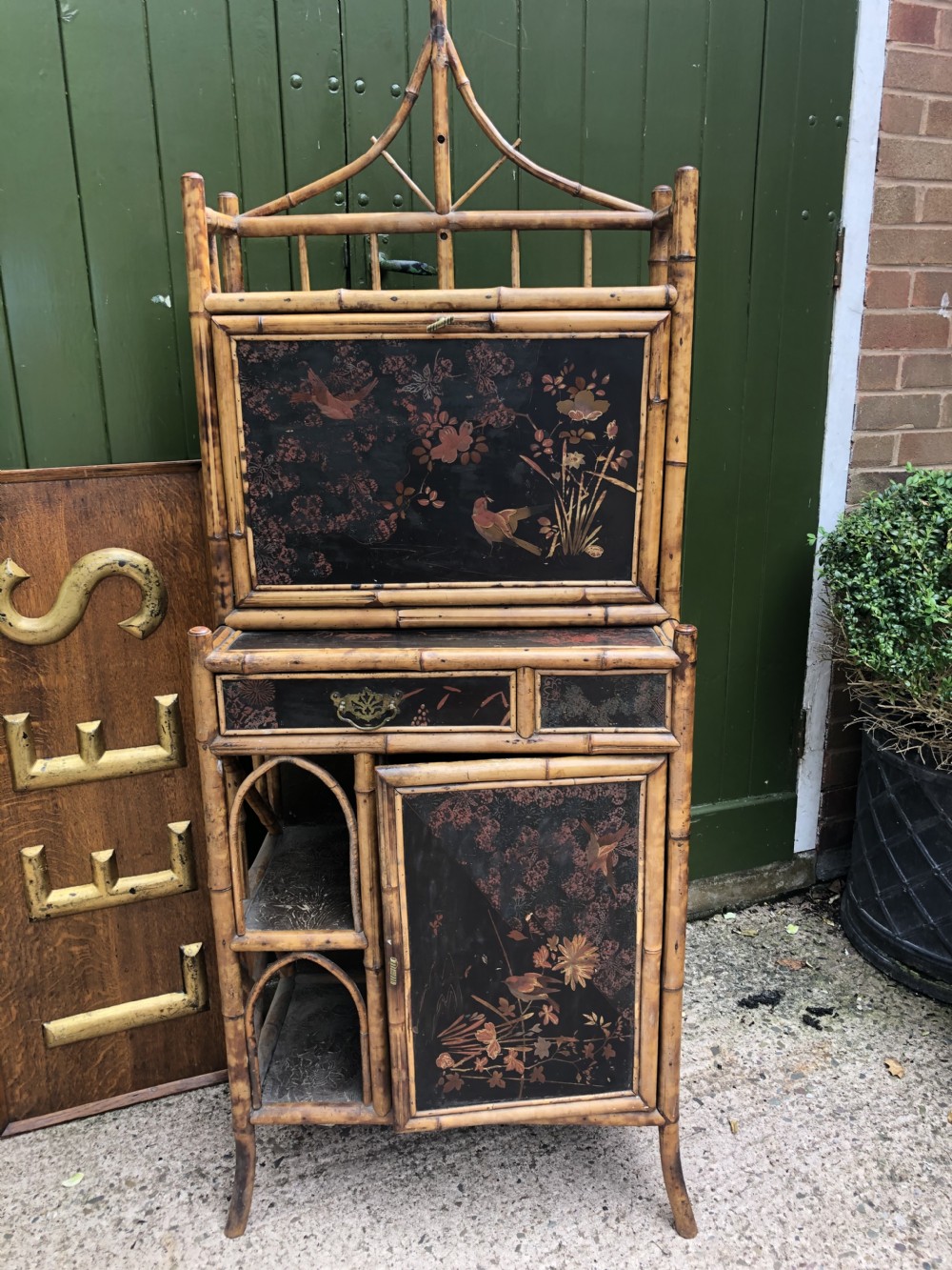 A late 19th-century bamboo escritoire cabinet featuring a pagoda-shaped top finial, a lacquered drop-front writing slope, side shelves, and a lower lacquered cupboard door decorated with floral motifs. View XXIV