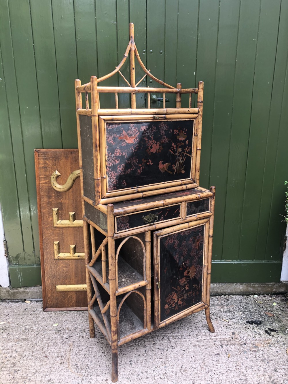 A late 19th-century bamboo escritoire cabinet featuring a pagoda-shaped top finial, a lacquered drop-front writing slope, side shelves, and a lower lacquered cupboard door decorated with floral motifs. View XXV