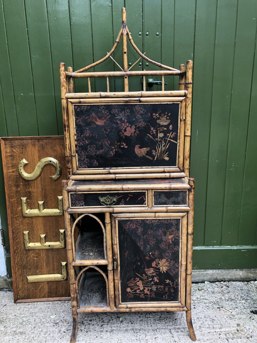 A late 19th-century bamboo escritoire cabinet featuring a pagoda-shaped top finial, a lacquered drop-front writing slope, side shelves, and a lower lacquered cupboard door decorated with floral motifs. View XXVI
