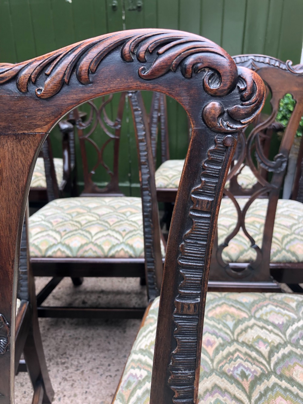 A set of eight carved mahogany Chippendale style dining chairs with decorative pierced back splats and patterned upholstered seats. View V