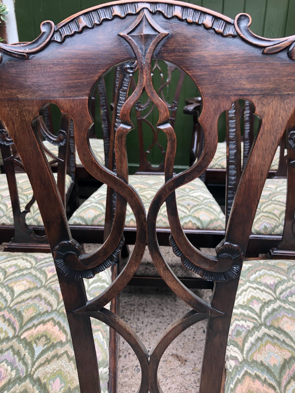 A set of eight carved mahogany Chippendale style dining chairs with decorative pierced back splats and patterned upholstered seats. View VI
