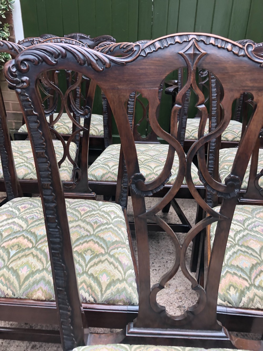 A set of eight carved mahogany Chippendale style dining chairs with decorative pierced back splats and patterned upholstered seats. View VII