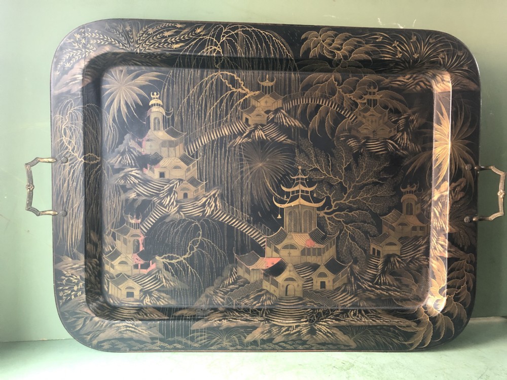 A rectangular black lacquered Regency papier-mache tray featuring gilded chinoiserie landscape decoration and two brass side handles. View II