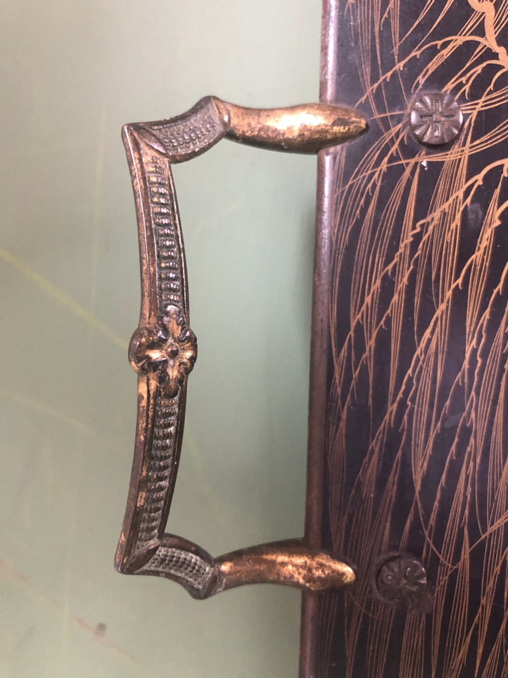 A rectangular black lacquered Regency papier-mache tray featuring gilded chinoiserie landscape decoration and two brass side handles. View V