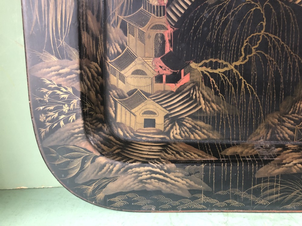 A rectangular black lacquered Regency papier-mache tray featuring gilded chinoiserie landscape decoration and two brass side handles. View IX