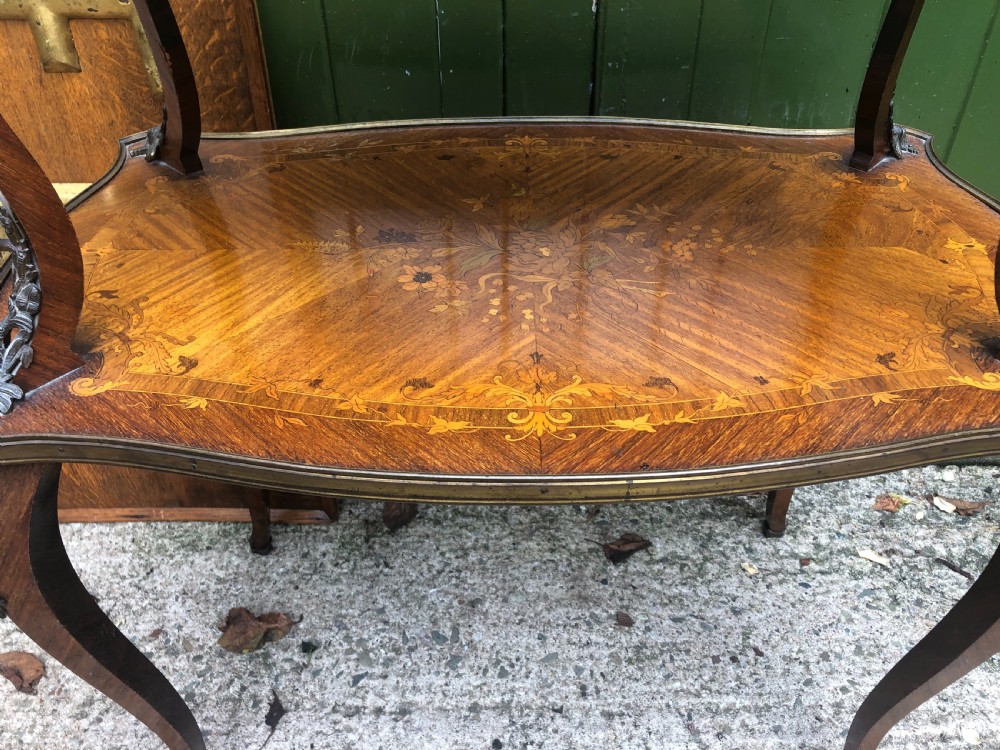 An early nineteenth-century French two-tier etagere table featuring detailed floral marquetry inlay, cabriole legs, brass galleries, and metal side handles. View V