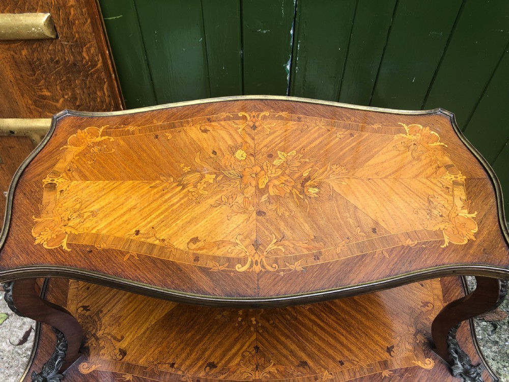An early nineteenth-century French two-tier etagere table featuring detailed floral marquetry inlay, cabriole legs, brass galleries, and metal side handles. View VI