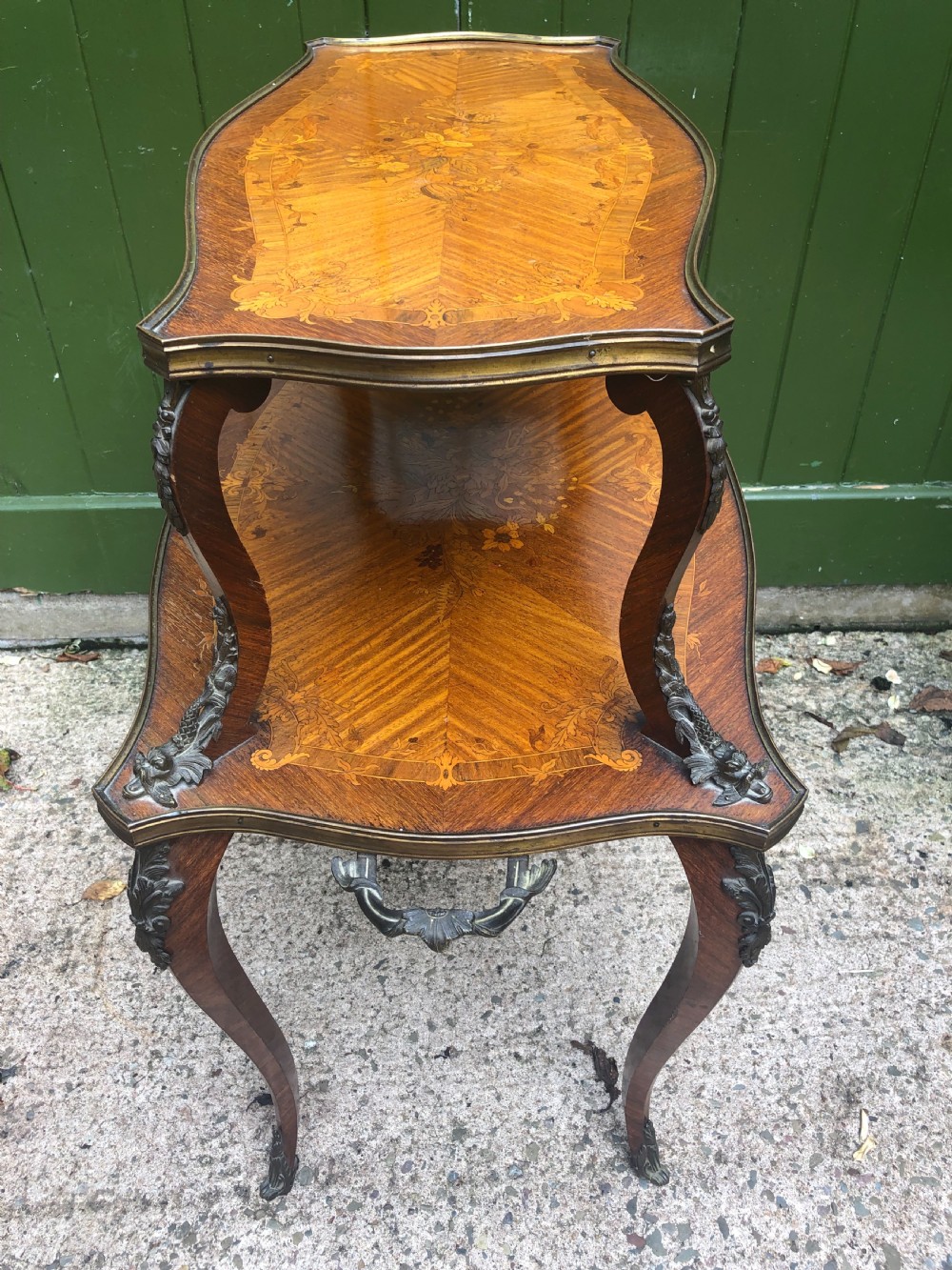 An early nineteenth-century French two-tier etagere table featuring detailed floral marquetry inlay, cabriole legs, brass galleries, and metal side handles. View X