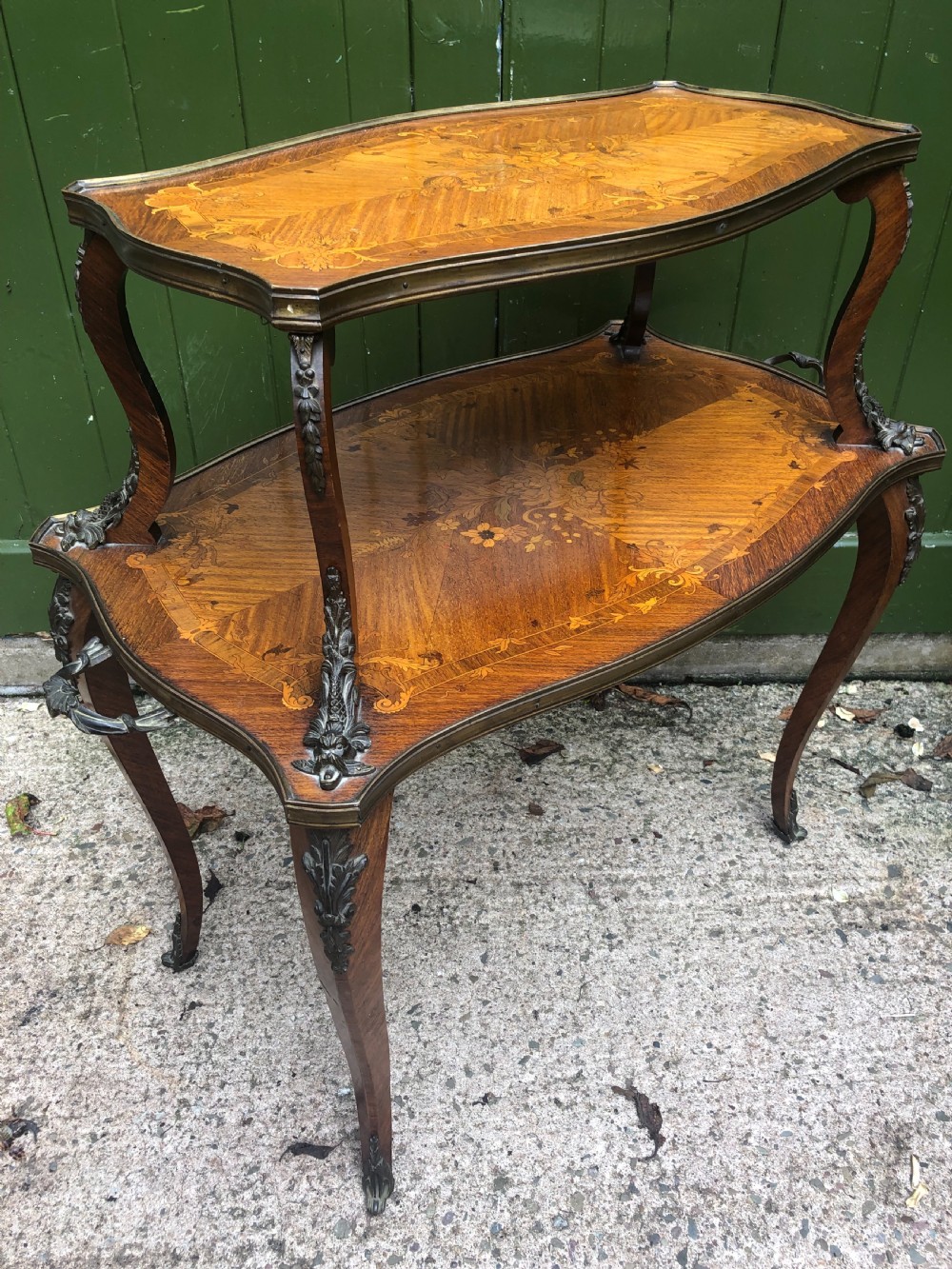An early nineteenth-century French two-tier etagere table featuring detailed floral marquetry inlay, cabriole legs, brass galleries, and metal side handles. View XVI