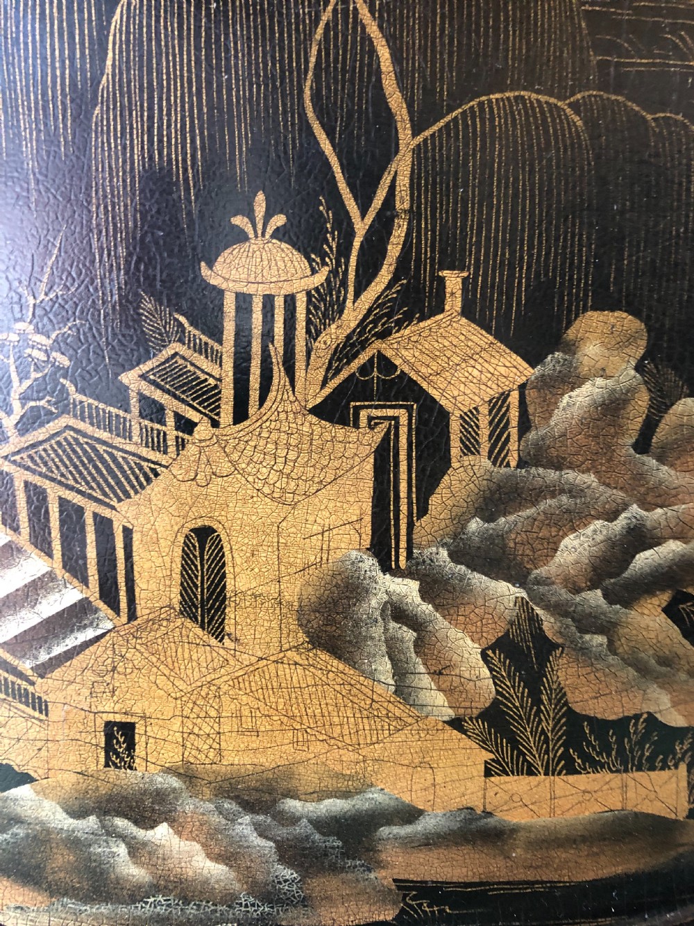 An oval black papier-mache tray featuring detailed gold chinoiserie landscape decoration and two side handles. View X