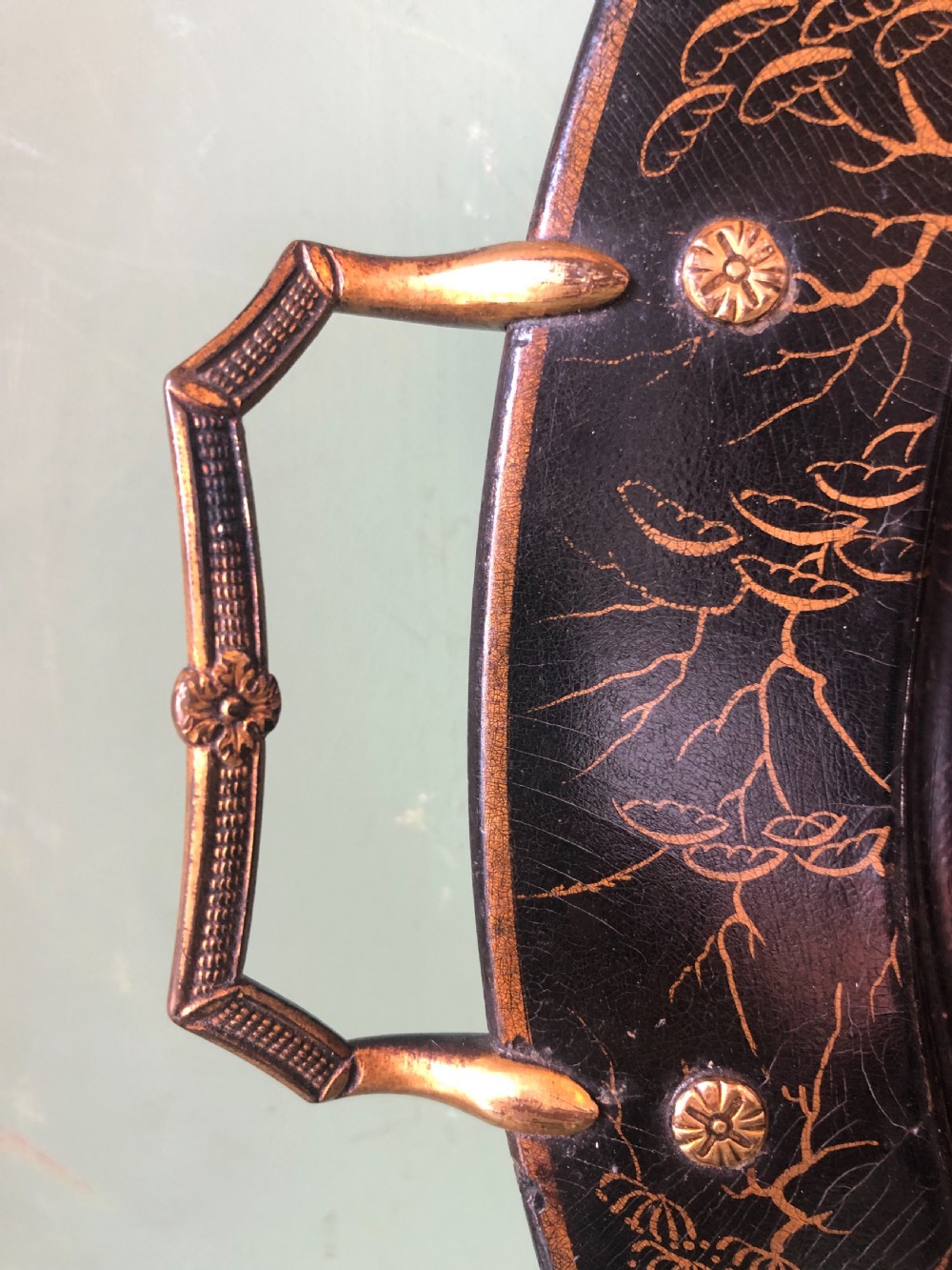 An oval black papier-mache tray featuring detailed gold chinoiserie landscape decoration and two side handles. View XII