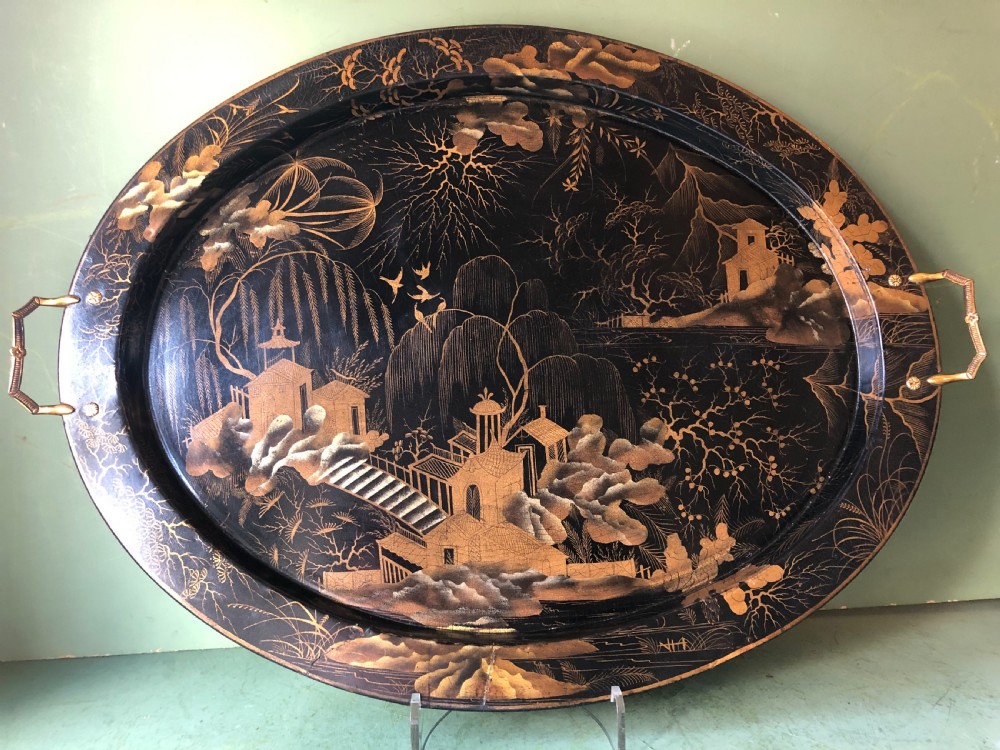 An oval black papier-mache tray featuring detailed gold chinoiserie landscape decoration and two side handles. View XIV